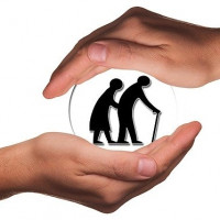 Schützende Hände legen sich um ein Seniorenpaar, das im Schattenriß zu sehen ist
